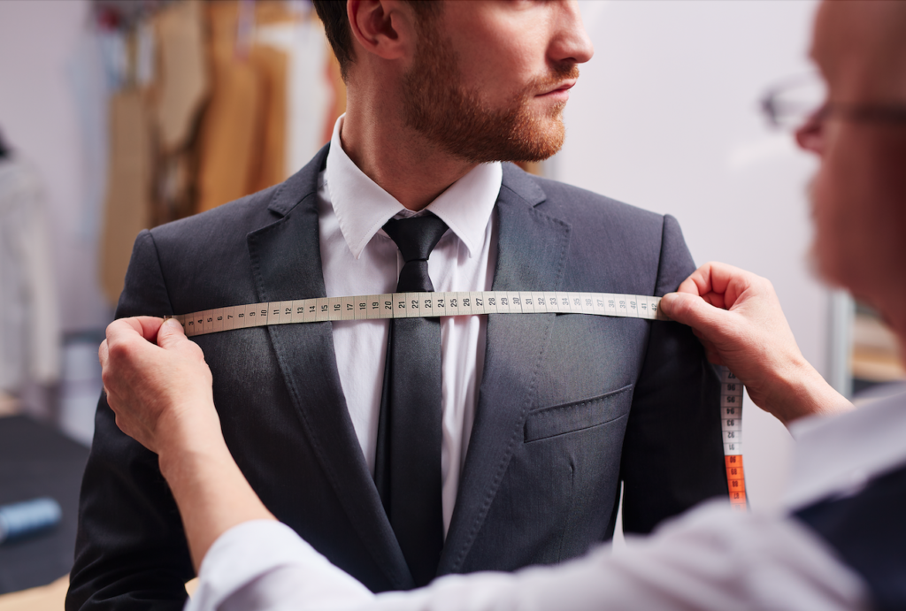 Man in suit getting measured by tailor.